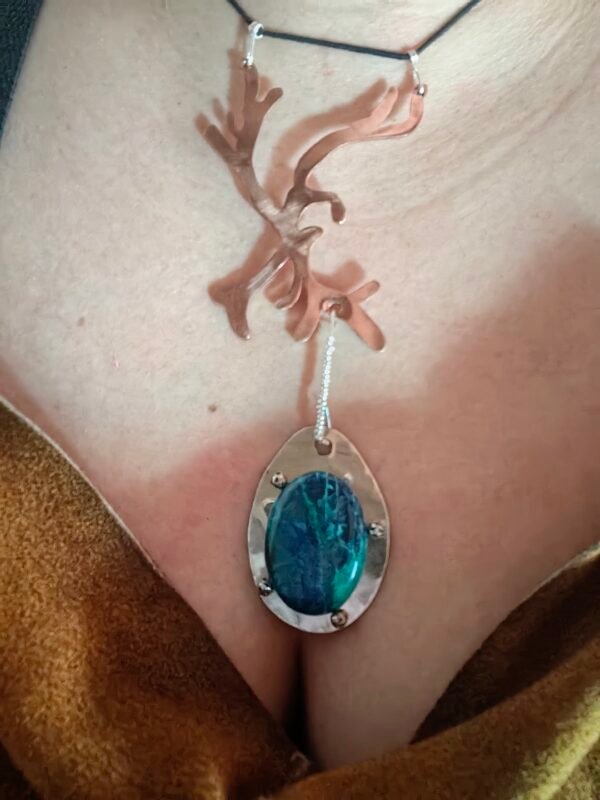 Pendentif Écho de la Mer porté, mettant en valeur le design inspiré par la mer et la branche de corail en cuivre