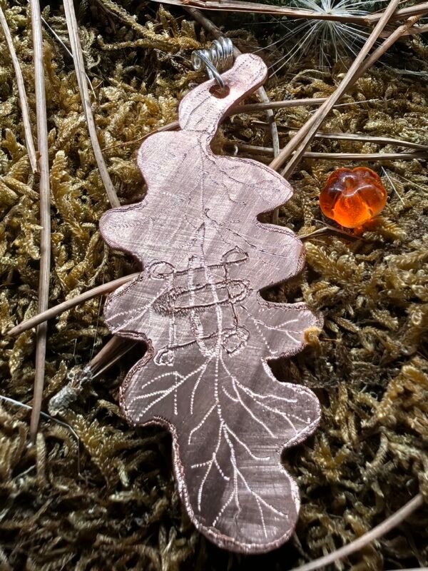 Vue avant du pendentif 'La Protection de Samhain' en forme de feuille de chêne en cuivre.