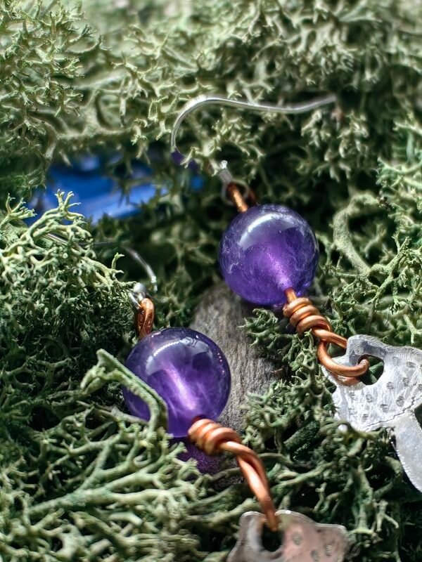 Gros plan sur les détails des champignons en argent et perles d'améthyste des boucles d'oreilles.