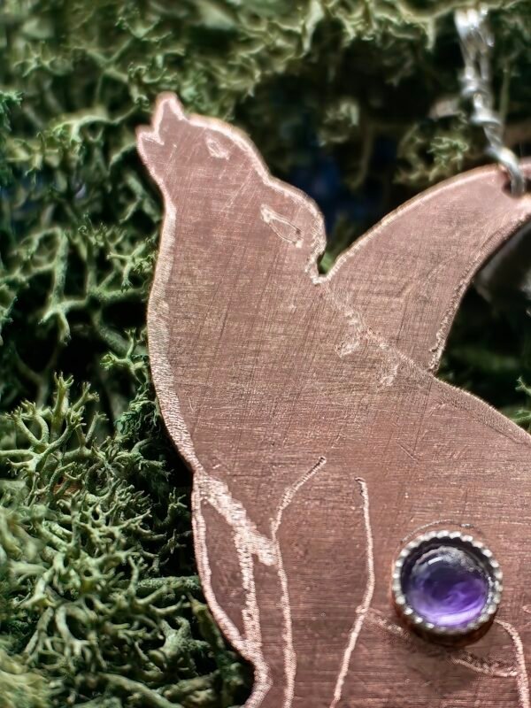 Détail du loupdu pendentif 'La Complainte sous la Lune' en argent et cuivre éthiques fait main en France sur de la mousse végétale naturelle.
