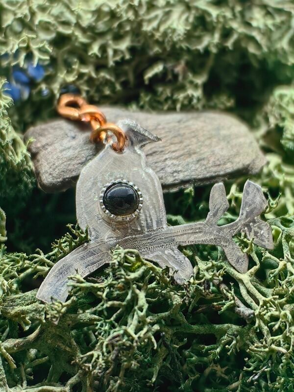 Pendentif 'La Sagesse du Merle' en argent et cuivre éthiques serti argent d'une obsidienne noire, fait main en France sur de la mousse végétale naturelle.