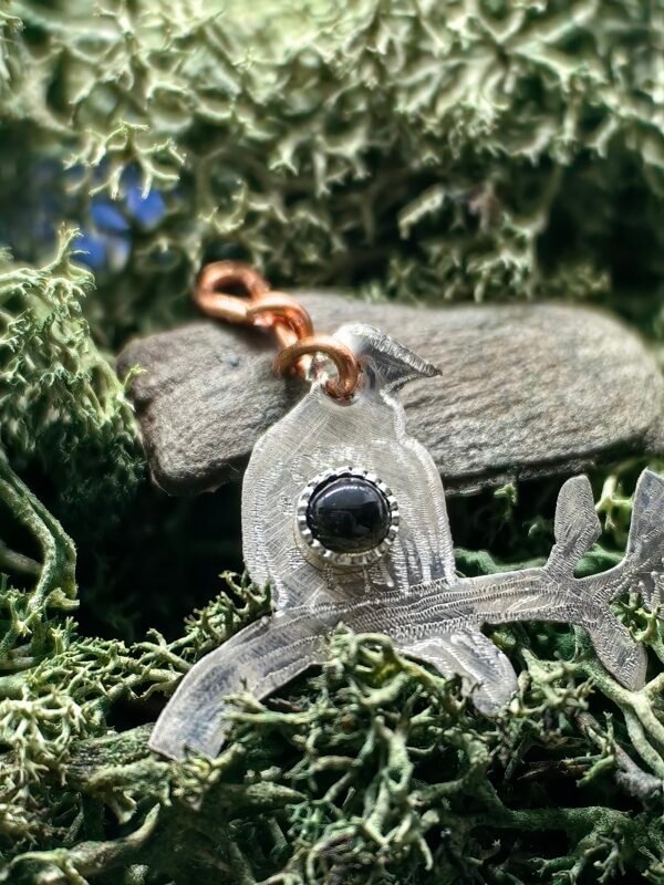 Détail du serti argent de l'obsidienne noire du pendentif 'La Sagesse du Merle', en argent et cuivre éthiques, hypoallergénique, fait main en France sur de la mousse végétale naturelle de chez L Chêne Enchanté.