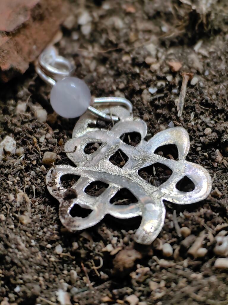 Pendentif celtique "trèfle" en argent et quartz rose de la collection Artéfacts, chez Le Chêne Enchanté. Le bijou repose sur un lit de terre de mon jardin, tel un artéfact qui aurait passé des siècles sous terre et qui vient d'être déterré par un archéologue ou historien. Bijou fait main dans le sud de la France.
Dans la tradition celtique, chaque feuille représente une vertu spécifique : espoir, foi, amour et chance. Les druides croyaient que le trèfle à quatre feuilles avait le pouvoir d'éloigner les esprits maléfiques et d'attirer la bonne fortune.
Toute reproduction de mes bijoux est formellement interdite, vous engage à des poursuites au pénal.