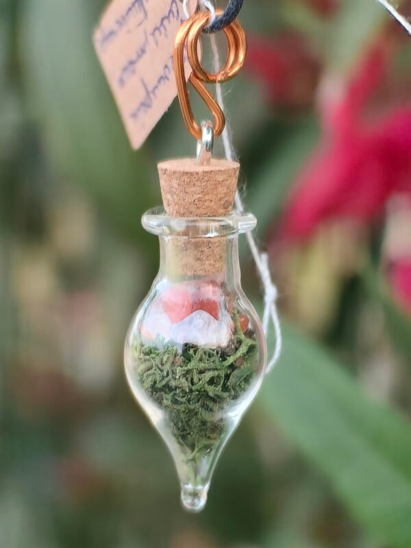 Pendentiif fiole "Potion des fées" aventurine rouge et mousse végétale naturelle monté sur cuivre. Collection Artéfacts chez Le Chêne Enchanté. Gros plan sur le pendentif.