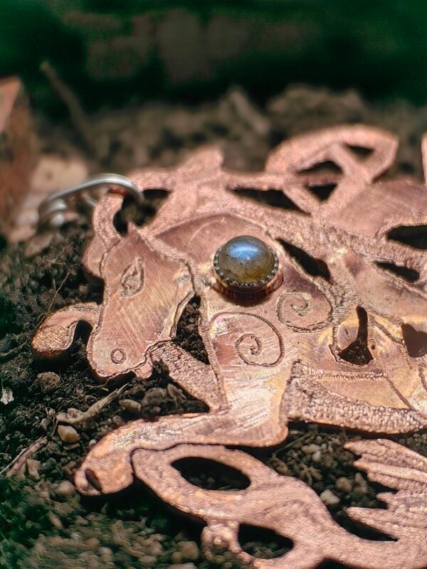 Pendentif "Cheval des mer" argent-cuivre et labradorite, collection Artéfacts chez Le Chêne Enchanté. Pendentif posé sur la terre de mon jardin comme un ancien trésor qu'un archéologue ou un historien aurait découvert après des siècles passés sous terre. Vu sur le haut du pendentif avec la tête du cheval, la labradorite serti argent clos, les spirales.