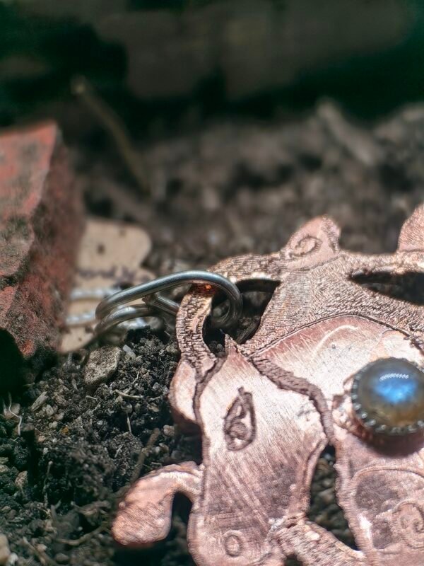 Pendentif "Cheval des mer" argent-cuivre et labradorite, collection Artéfacts chez Le Chêne Enchanté. Pendentif posé sur la terre de mon jardin comme un ancien trésor qu'un archéologue ou un historien aurait découvert après des siècles passés sous terre. Vu sur la labradorite serti clos argent et les spirales et tête du cheval.