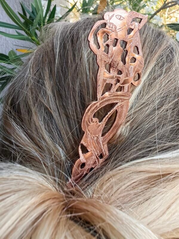 Vu de près du pic à cheveux en cuivre pur "grande bête nordique" collection artéfacts chez Le Chêne Enchanté porté pour composer un chignon.
