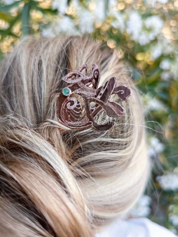 Pic à cheveux "oiseau nordique" argent-cuivre éthique et aventurine verte, porté dans une chevelure, collection artéfact. Gros plan sur l'oiseau nordique et son aventurine verte serti en argent.