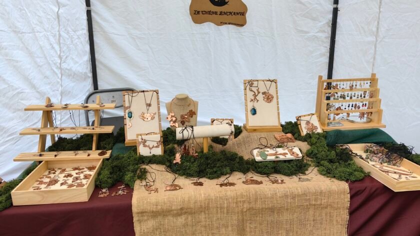 Stand de mon échoppe itinérante Le Chêne Enchanté lors d'une médiévale. Vu de près de mon stand avec ma table d'exposition contenant mes bijoux talismans-guides historiques joailliers éthiques, mon logo et le nom de mon entreprise. Crédit photo Le Chêne Enchanté, toutes reproductions de mon stand que ce soit ses couleurs, ses décorations et mes bijoux sont formellement interdites.