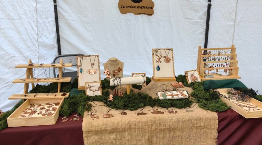 Stand de mon échoppe itinérante Le Chêne Enchanté lors d'une médiévale. Vu de près de mon stand avec ma table d'exposition contenant mes bijoux talismans-guides historiques joailliers éthiques, mon logo et le nom de mon entreprise. Crédit photo Le Chêne Enchanté, toutes reproductions de mon stand que ce soit ses couleurs, ses décorations et mes bijoux sont formellement interdites.