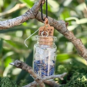 Pendentif fiole Talisman des fées, cuivre, cristal de roche, fleurs de bleuet, verre, bouchon de liège de chêne, collection Artéfacts chez Le Chêne Enchanté. Le pendentif est suspendu à une branche de chêne entouré de mousse végétale naturelle. Ce pendentif renferme un micro univers de magie, de protection, de lumière et de sérénité. Il est un doux monde féérique qui porte en lui la mémoire des savoir oubliés des plantes des herboristes. Ce bijou est mixte. Vu d'ensemble du pendentif fiole Talisman des fées. Tous les bijoux et photographies appartiennent exclusivement à : Le Chêne Enchanté. Toute reproduction est strictement interdite.