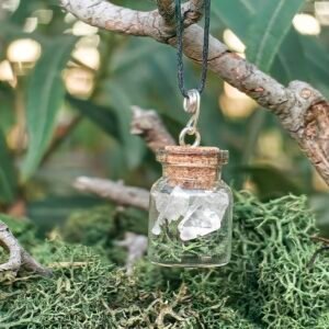 Pendentif fiole Potion des fées, argent, cristal de roche, mousses naturelle végétale, verre et bouchon de liège de chêne, collection Artéfacts chez Le Chêne Enchanté. Le pendentif repose sur une branche de chêne entourée de mousse naturelle végétale de la forêt. Le pendentif fiole Potion des fées apporte clarté, ancrage, vision et mémoire de la Terre. Vu entière du pendentif. Tous les bijoux et photographies appartiennent exclusivement à : Le Chêne Enchanté. Toute reproduction est strictement interdite.